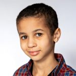 Boy with plaid shirt give the camera a slight smirk on photo day